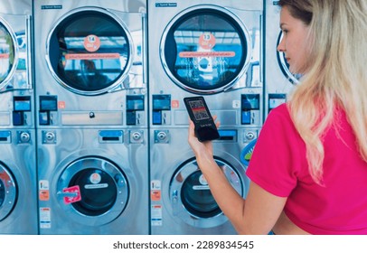 Young woman pays for laundry service using phone and banking application - Powered by Shutterstock