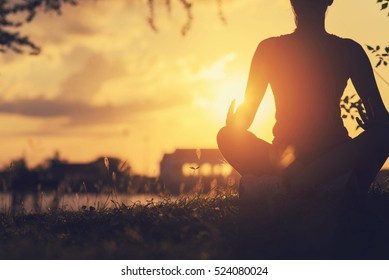 Young Woman Peacefully Meditating In A Open Field. 