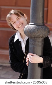 A Young Woman Peeking Around A Lamppost Smiling