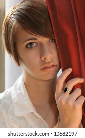 Young Woman Peeking Through Curtain