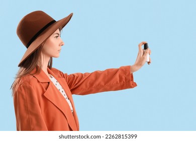 Young woman with pepper spray for self-defence on blue background