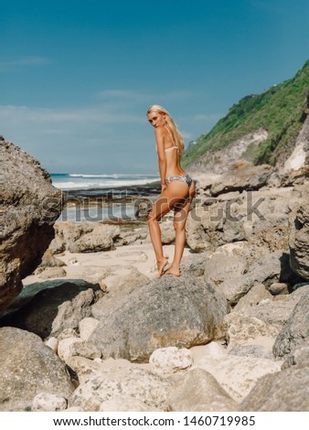 Young woman with perfect body in bikini posing at tropical beach.