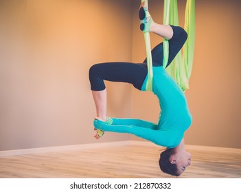 Young woman performing antigravity yoga exercise 