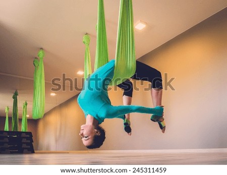 Young woman performing antigravity yoga exercise 