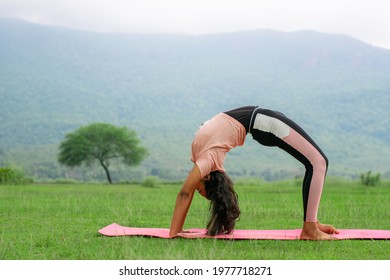 Young woman performing Chakrasana Yoga pose outdoor, doing Bridge pose, Urdhva Dhanurasana also known as Wheel posture