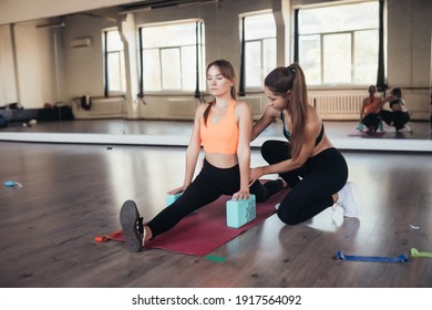 Young woman personal trainer helping with workout at gym