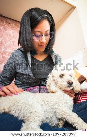 A young woman petting her little dog in her bedroom