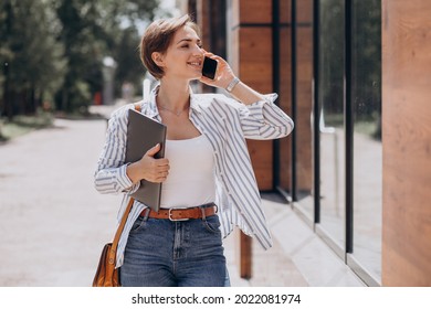 Young Woman With Phone And Computer Walking Outside The Street