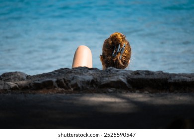 Young woman photographed on the Cres island beach, Croatia,  while reading book and sunbathing at the same time - Powered by Shutterstock