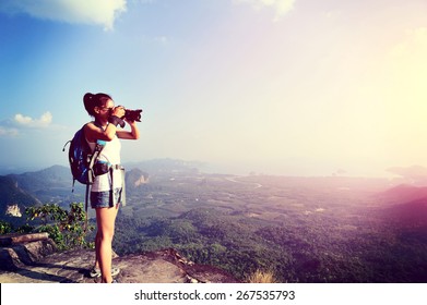 young woman photographer taking photo at mountain peak