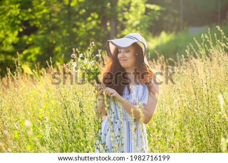 Young woman picking flowers in the meadow in summer evening