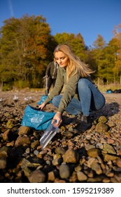 Young Woman Picking Up Plastic At Rocky Beach