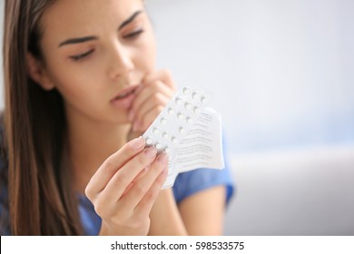 Young woman with pills at home, closeup. Gynecology concept