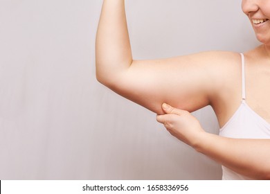 Young woman pinch fat arm. Self hand pinching body. Fenale person showing overweight triceps.