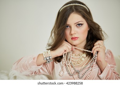 Young woman in pink dress with pearl necklace and diadem in hair.                