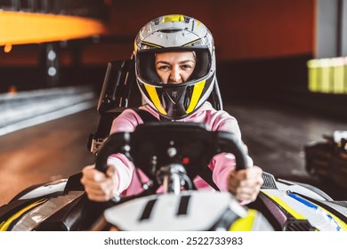 Young woman in a pink hoodie and helmet focused during a go-kart race on an indoor track. - Powered by Shutterstock