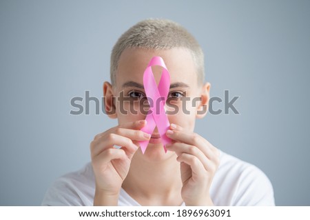 Young woman with pink ribbon on a white background. Mammary cancer