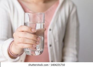 Young woman with pink shirt and white sweater holding drinking water glass in her hand. Health care concept.Room temperature water. - Shutterstock ID 1404231710