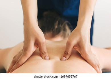 Young woman in pink shorts receiving a back massage in a spa center. Female patient is receiving treatment by professional therapist with beautiful hands. Body positive, harmony, healthy lifestyle