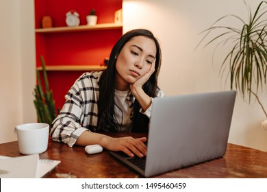 Young Woman In Plaid Shirt Sadly Looks At Laptop, Not Wanting To Work