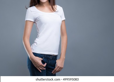 Young Woman In Plain White T-shirt And Blue Jeans Posing On Light Gray Background