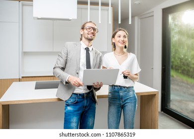 Young Woman Planning Interior With Designer Standing Together With Digital Tablet At The New Kitchen