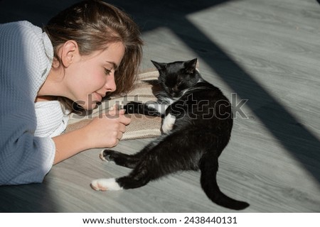Young woman play with fluffy cat. Cat lies near woman face. The fluffy black cat comfortably settled to sleep or to play. Kitty rest. Cute cozy morning place. Morning with cat at home. The pussycat.