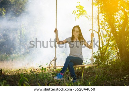 Young woman play swinging in the forest. over fog background.  Vintage tone.
