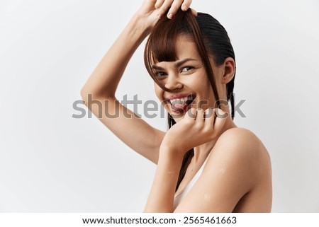 Young woman playfully posing with wet hair, smiling and making a funny face, against a clean white background Perfect for beauty and lifestyle concepts