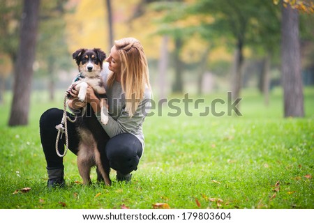 Young woman playing with Australian Shepherd dog outdoors in the park. 