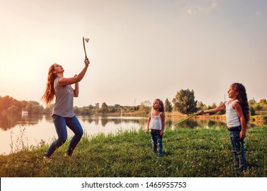 Young Woman Playing Badminton With Daughters In Summer Park. Family Having Fun Outdoors. Mother's Day