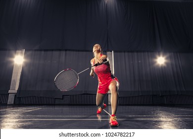 Young woman playing badminton over gym background
