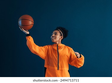 Young woman playing with a basketball in studio. Female in orange fitness wear with basketball practice moves. - Powered by Shutterstock