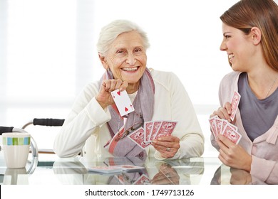 Young woman playing cards with a happy elderly woman in a retirement home - Powered by Shutterstock