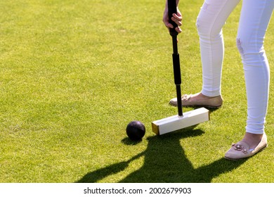 A Young Woman Is Playing Croquet On A Lawn