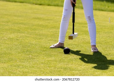 A Young Woman Is Playing Croquet On A Lawn