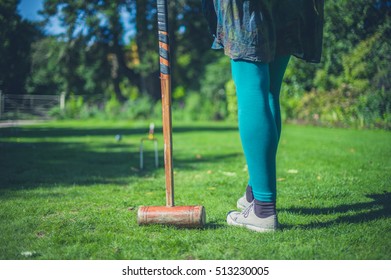 A Young Woman Is Playing Croquet On A Lawn