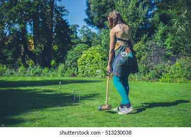 A Young Woman Is Playing Croquet On A Lawn