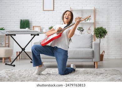 Young woman playing electric guitar and singing at home - Powered by Shutterstock