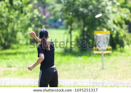Young woman playing flying disc sport game in the park
