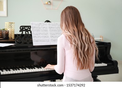 Young Woman Playing Grand Piano At Home