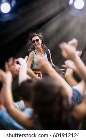 A Young Woman Playing Guitar On Stage During A Concert Outside, The Fans Have Their Arms Up. Shot With Flare