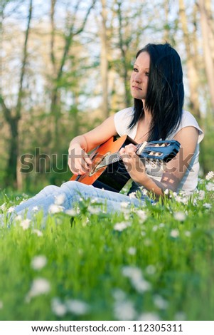 Young woman playing the guitar outdoors