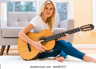 Young Woman Playing Her Guitar At Home