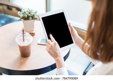 A Young Woman Is Playing An IPad At A Coffee Shop.