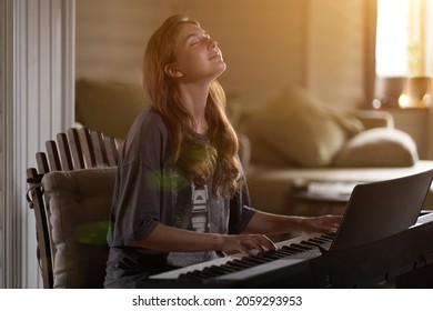 A young woman playing the piano.Close-up of a beautiful blonde girl with reddish-brown hair playing the piano creative, performance, musical concept, she wearing a T-shirt and playing a black piano.