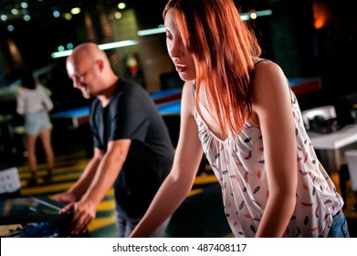 Young Woman Playing Pinball In Game Room