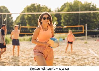young woman plays beach volleyball with friends