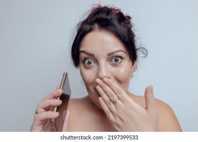 Young Woman Pleasantly Suprised Holding Phone And Her Hand Over Mouth