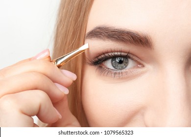 Young woman plucking eyebrow with tweezers, closeup